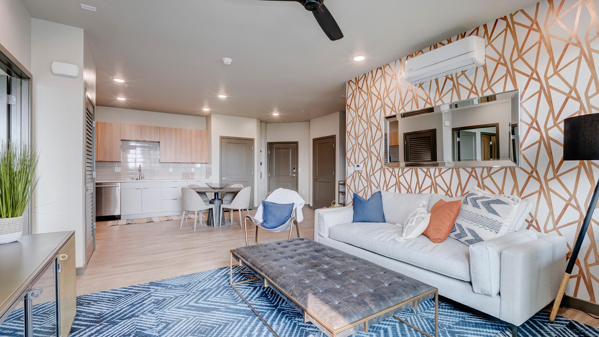 Living room with wood floor, rug, leather couch and coffee table, and geometric painted wall.