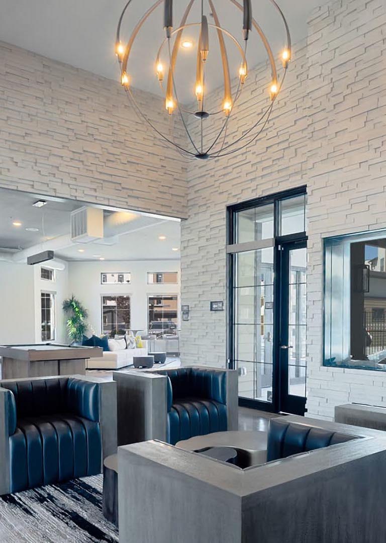 Azure apartments clubhouse with plush seating, large round light fixture, and textured walls.